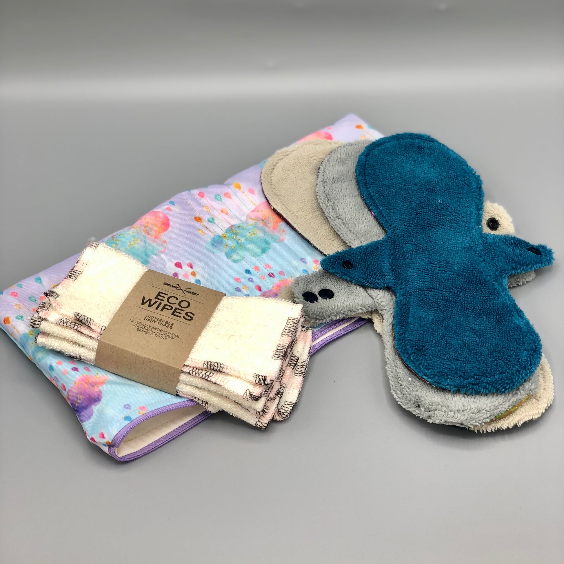 Different sizes of luxury bamboo, highly absorbent, reusable sanitary pads laid out on top of a waterproof lined wet and dry bag and displayed with a pack of bamboo eco wipes